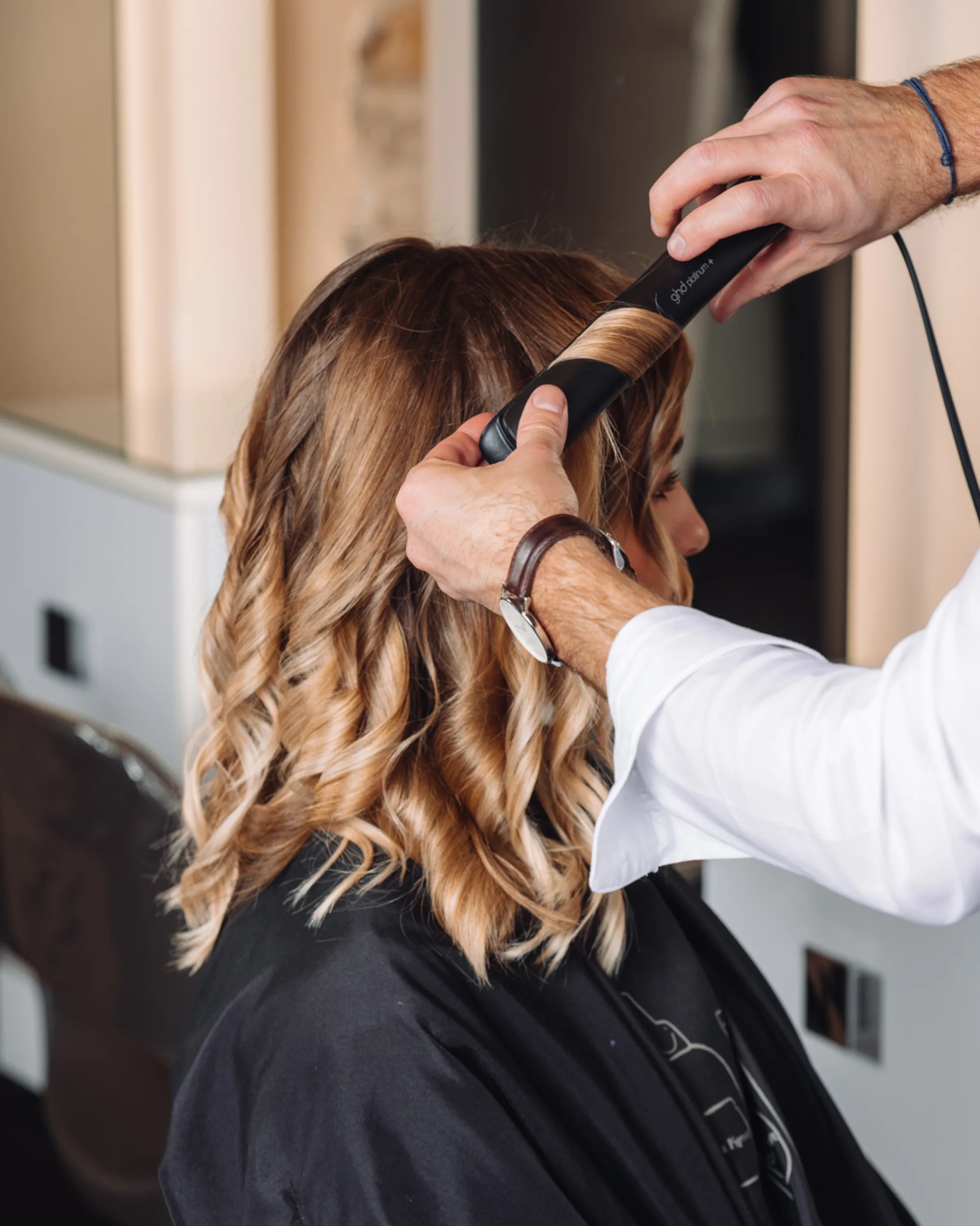 Balayage caramel et miel mis en boucles au fer par un coiffeur du salon